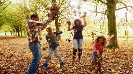 Family playing with autumn in woodlands